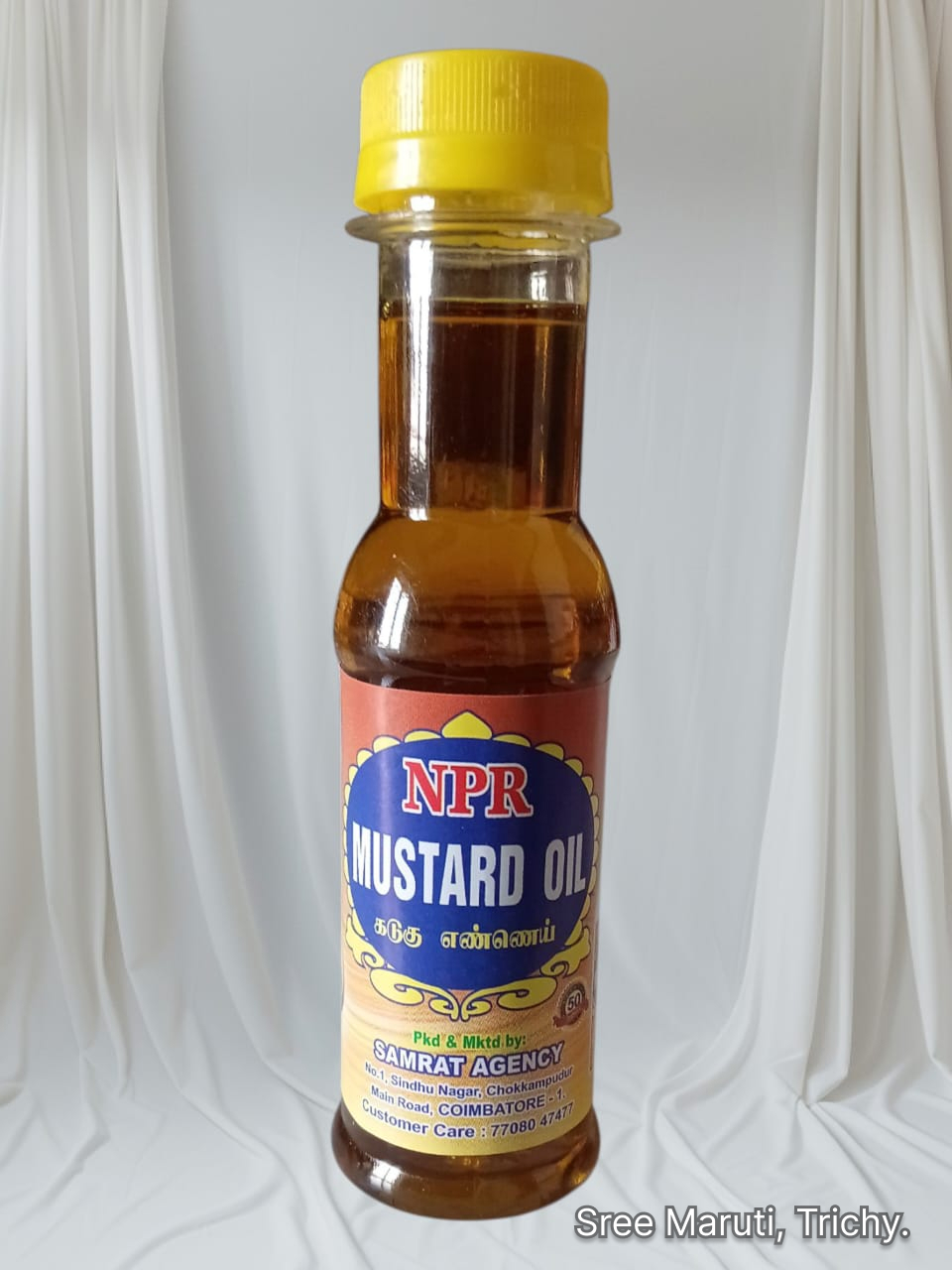 Pure mustard oil bottle with mustard seeds on a wooden surface.