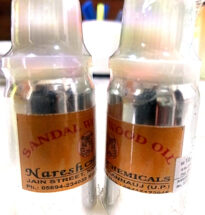 Bottle of sandalwood oil with sandalwood sticks and powder.