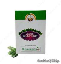 Vilwadi Gulika tablets in a container with Ayurvedic herbs like neem and bilva.