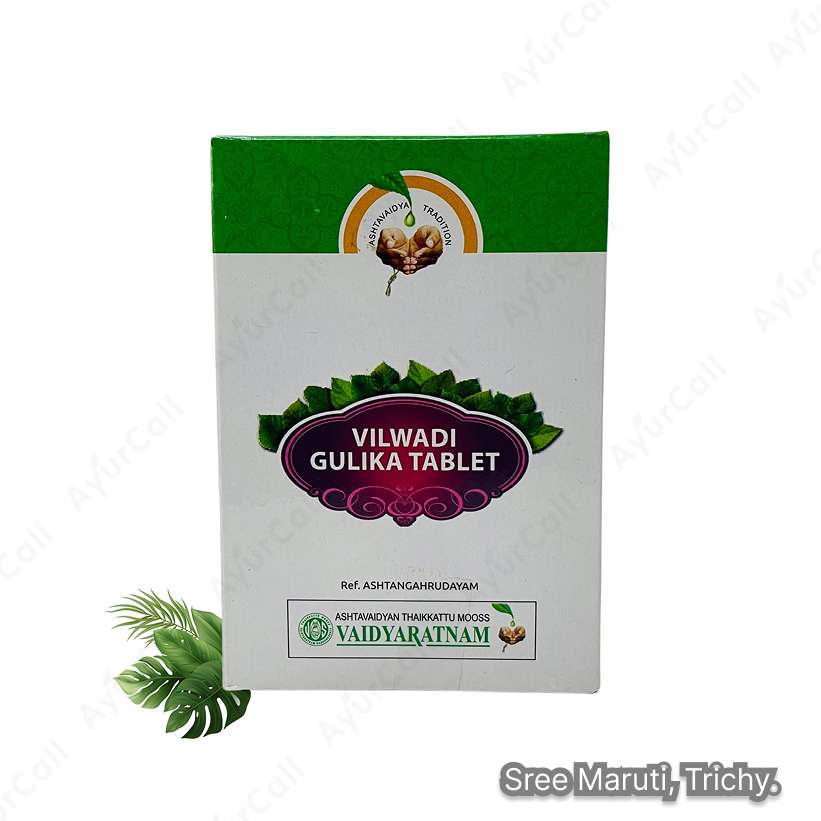 Vilwadi Gulika tablets in a container with Ayurvedic herbs like neem and bilva.